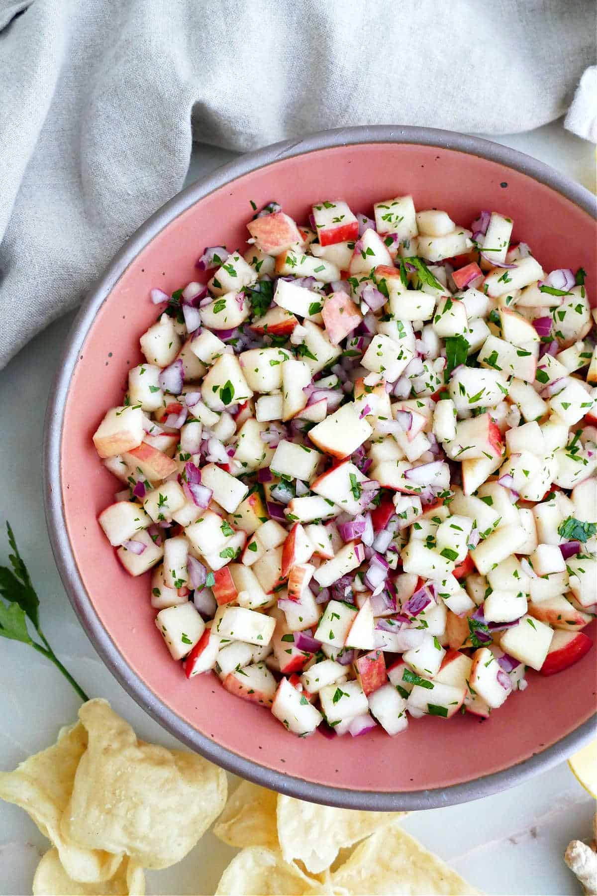Raw apple salad with onion, ginger, cider vinegar, and parsley in a bowl.