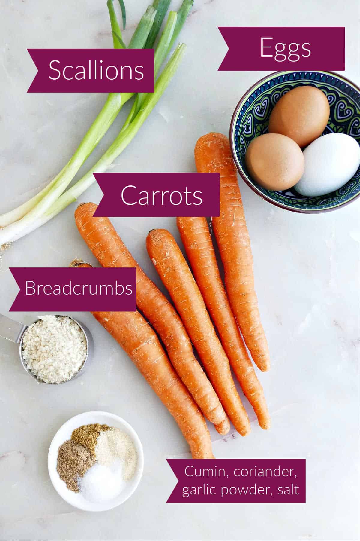 Scallions, eggs, carrots, spices, and breadcrumbs on a counter with labels.