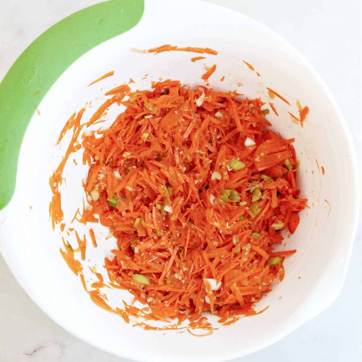 Batter for shredded carrot fritters in a large mixing bowl.