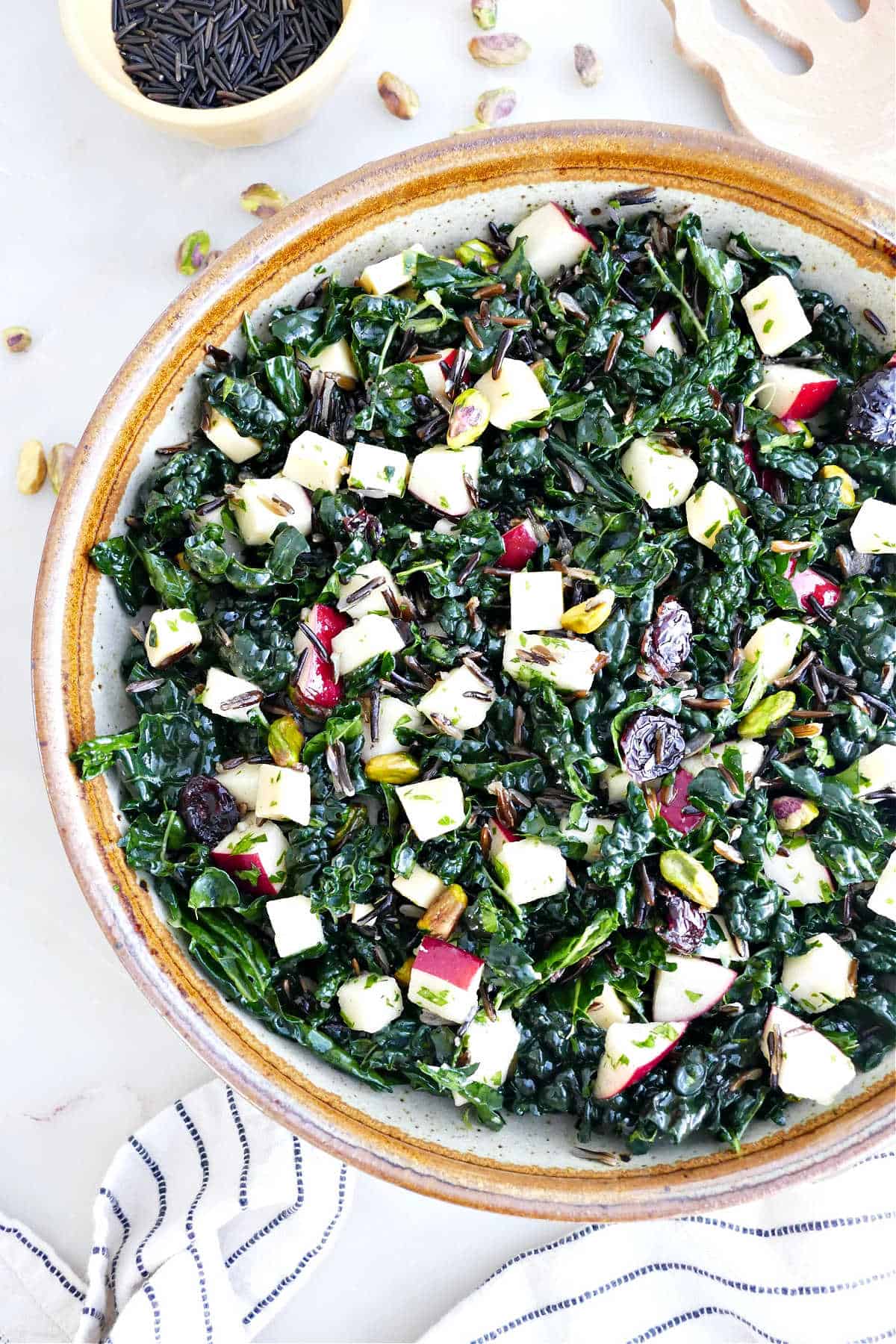 Kale salad with apples and wild rice in a serving bowl.