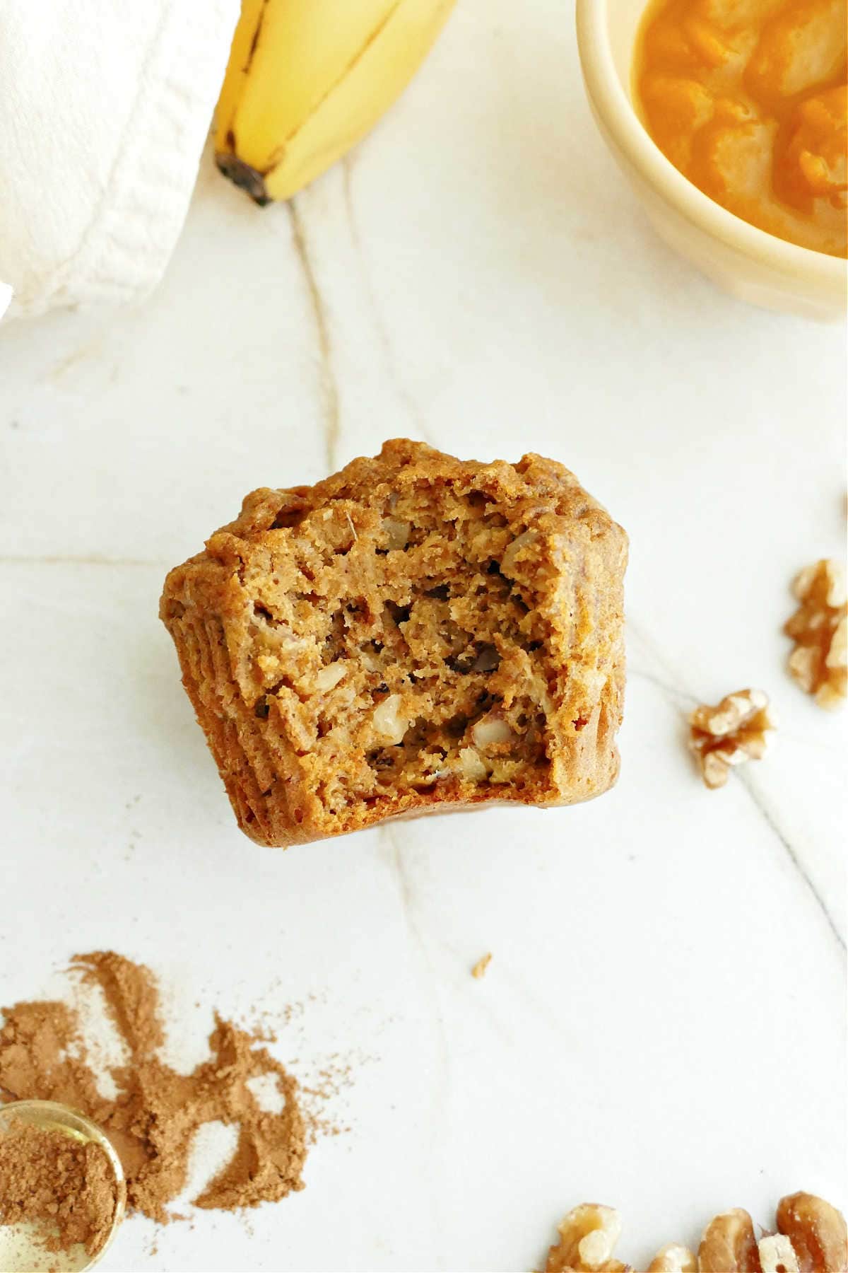 Banana pumpkin muffin with a bite taken out on a counter.