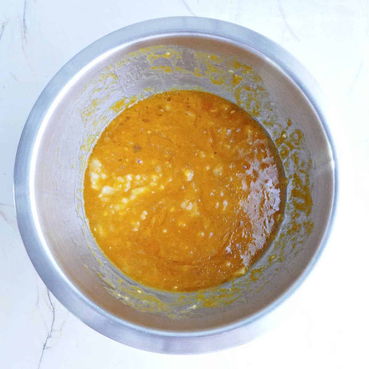 Wet ingredients for pumpkin muffins whisked together in a bowl.