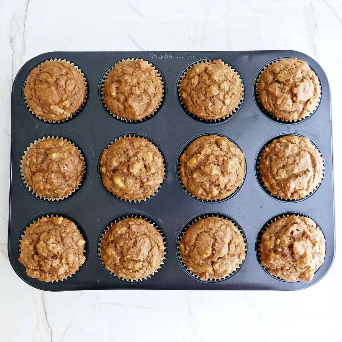Healthy banana pumpkin muffins in a muffin tin after coming out of the oven.