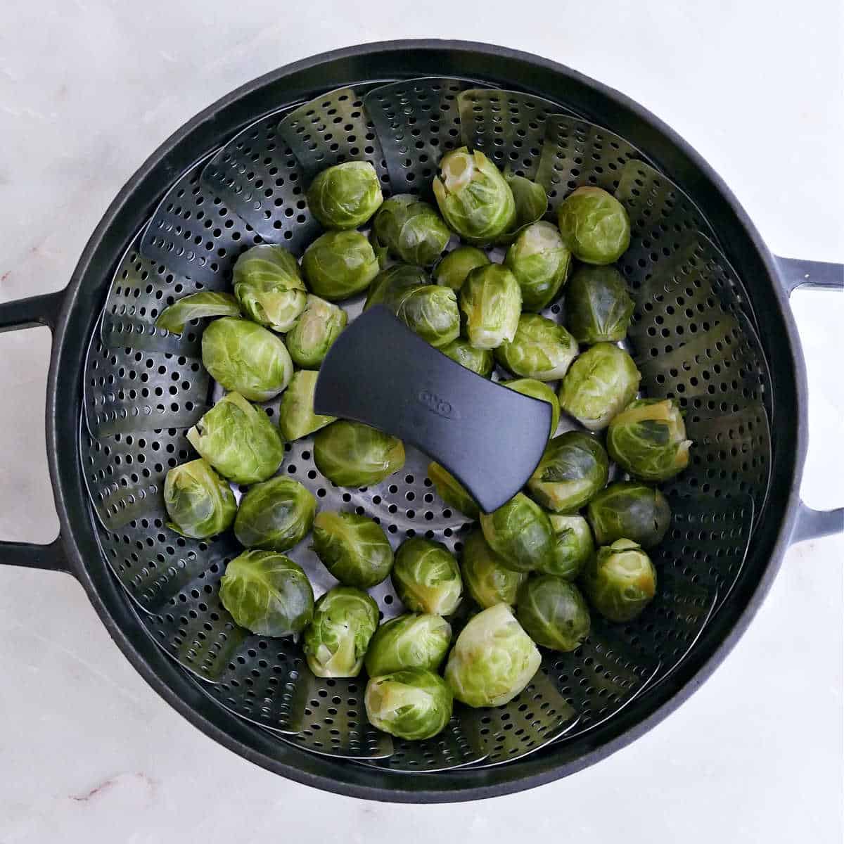 Brussels sprouts in a vegetable steamer basket in a pot.