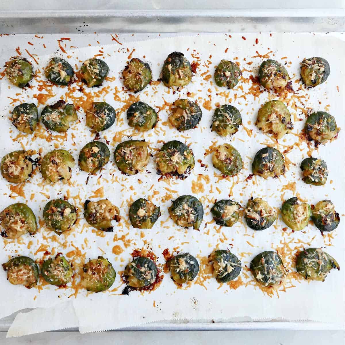 Smashed Brussels sprouts on a baking sheet after roasting in the oven.