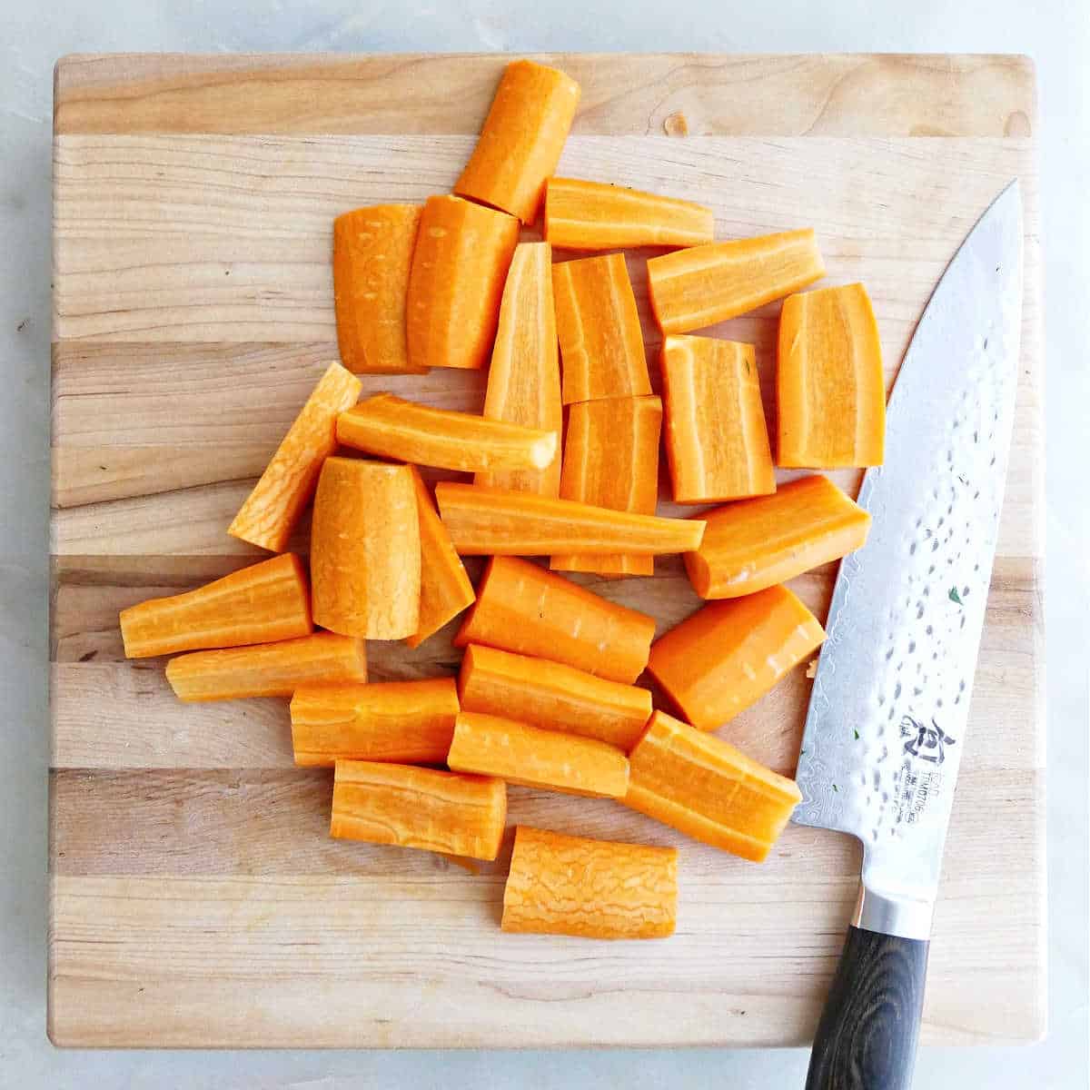 Carrots sliced into strips on a cutting board with a knife.