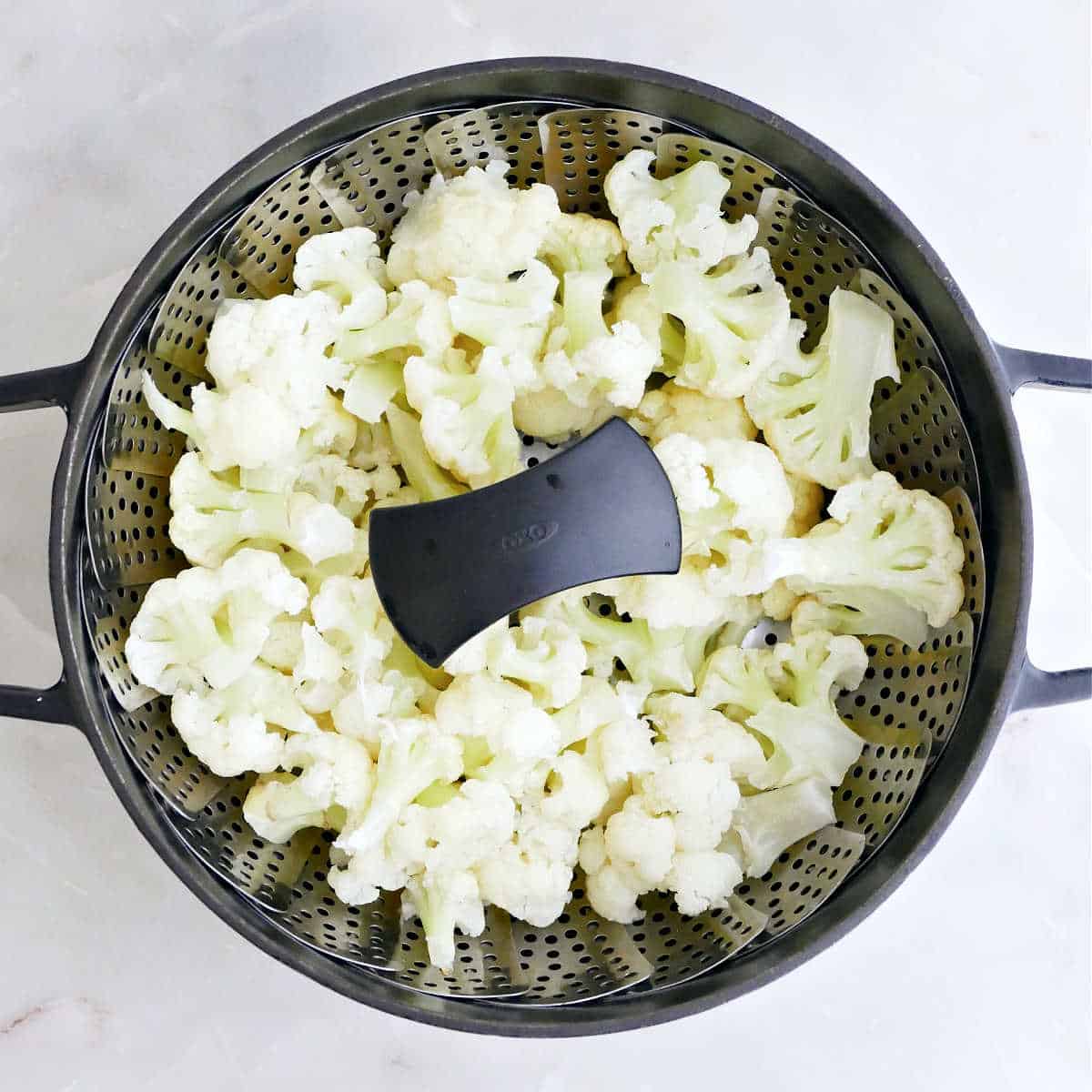 Steamed cauliflower in a veggie steamer in a pot.