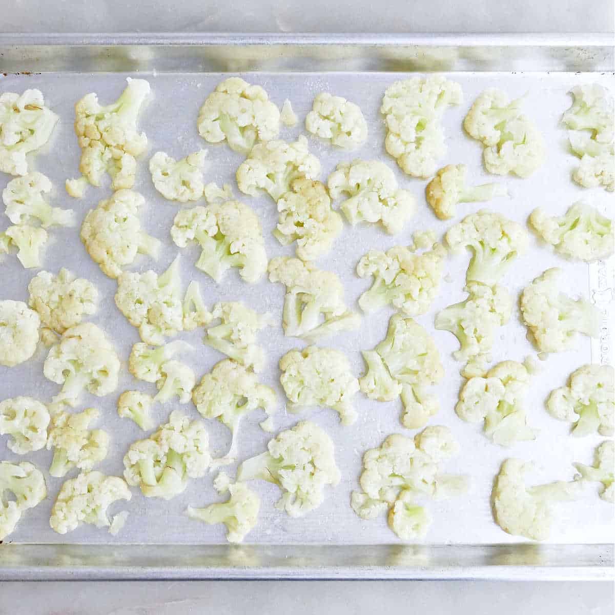 Steamed cauliflower smashed and spread on a baking sheet.
