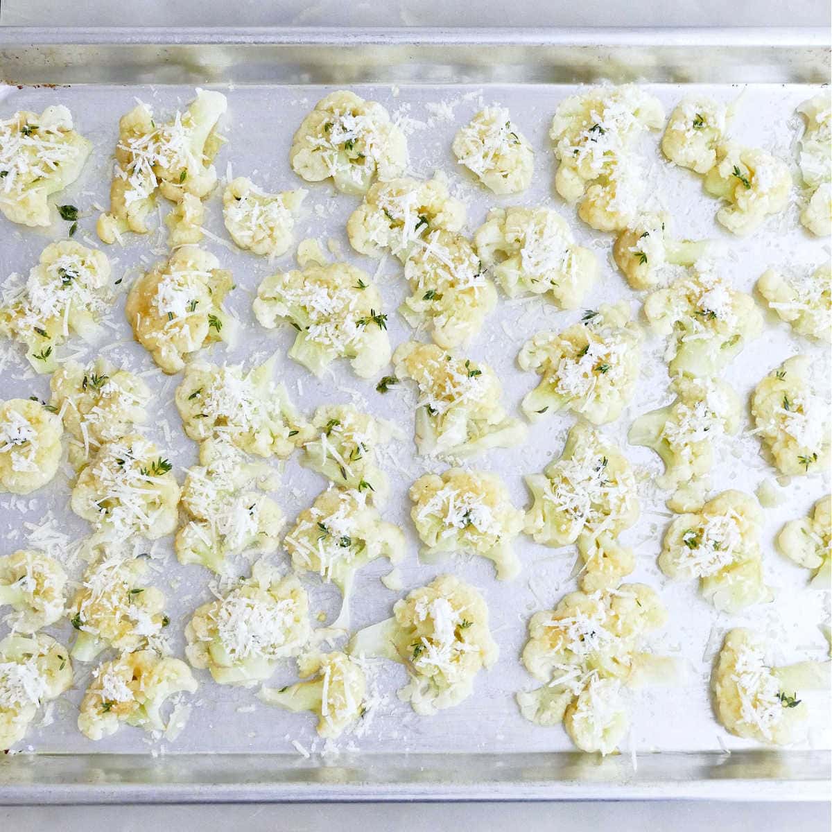 Smashed cauliflower brushed with oil and seasonings and sprinkled with cheese.