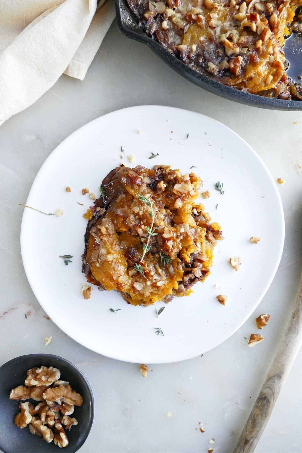 Serving of squash gratin on a plate garnished with thyme.
