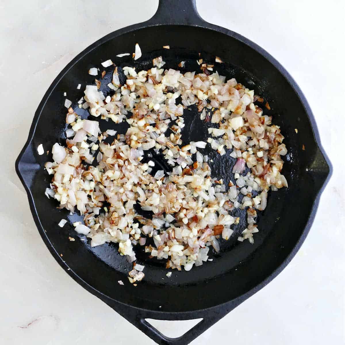 Onion and garlic cooking in olive oil in a skillet.