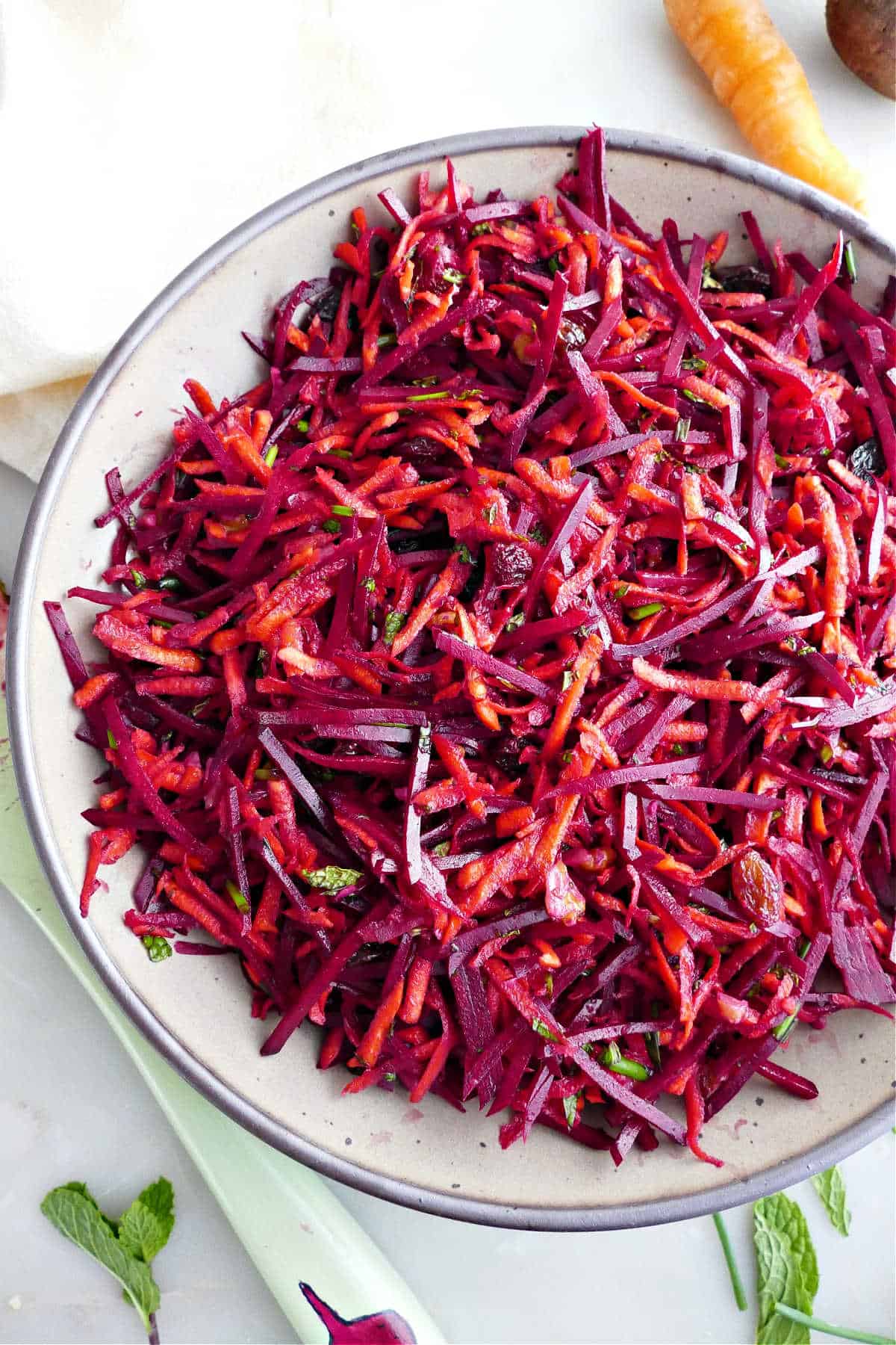 Shredded carrots and beets with dressing in a serving bowl.