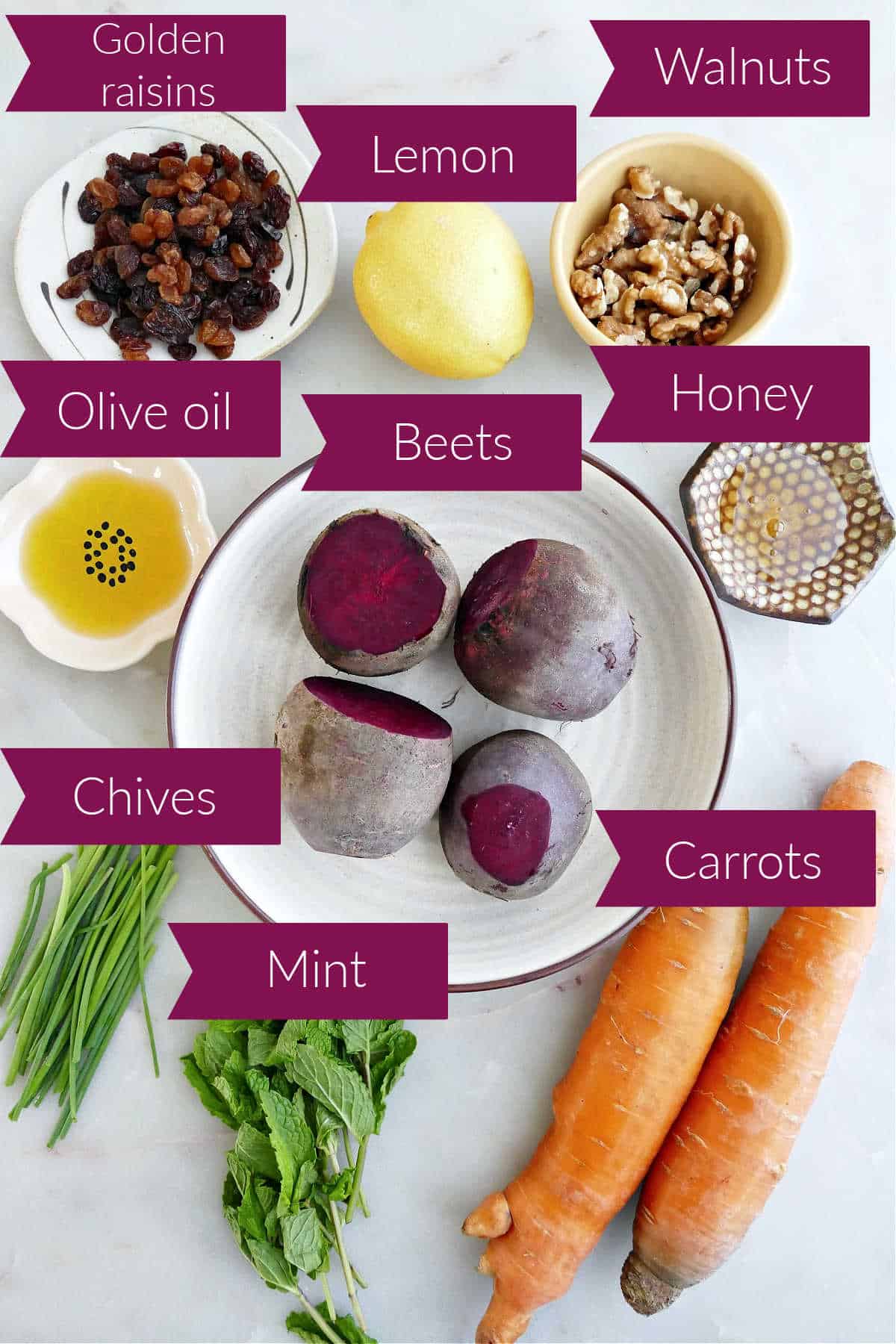 Raisins, lemon, walnut, oil, beets, honey, chives, mint, and carrots on a counter with labels.