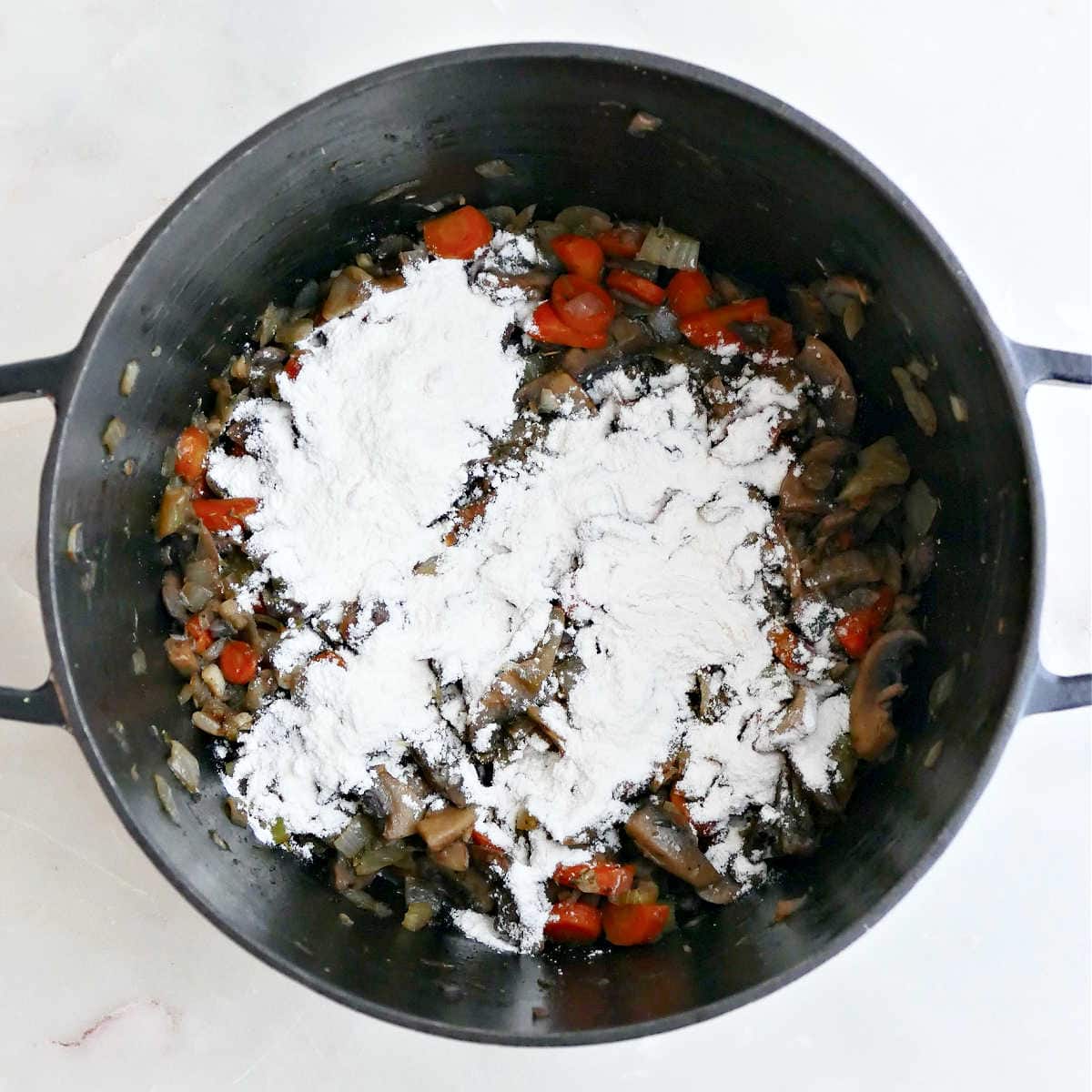 Cooked vegetables with wild rice and flour in a soup pot.