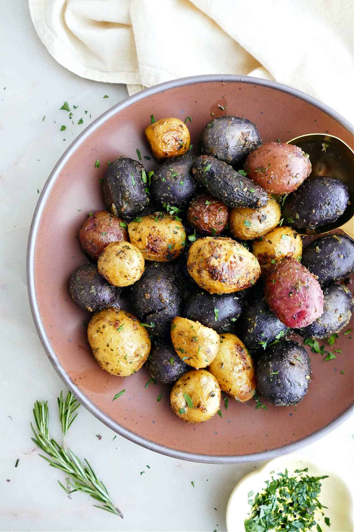 Roasted rainbow dutch oven potatoes with herbs in a serving bowl.