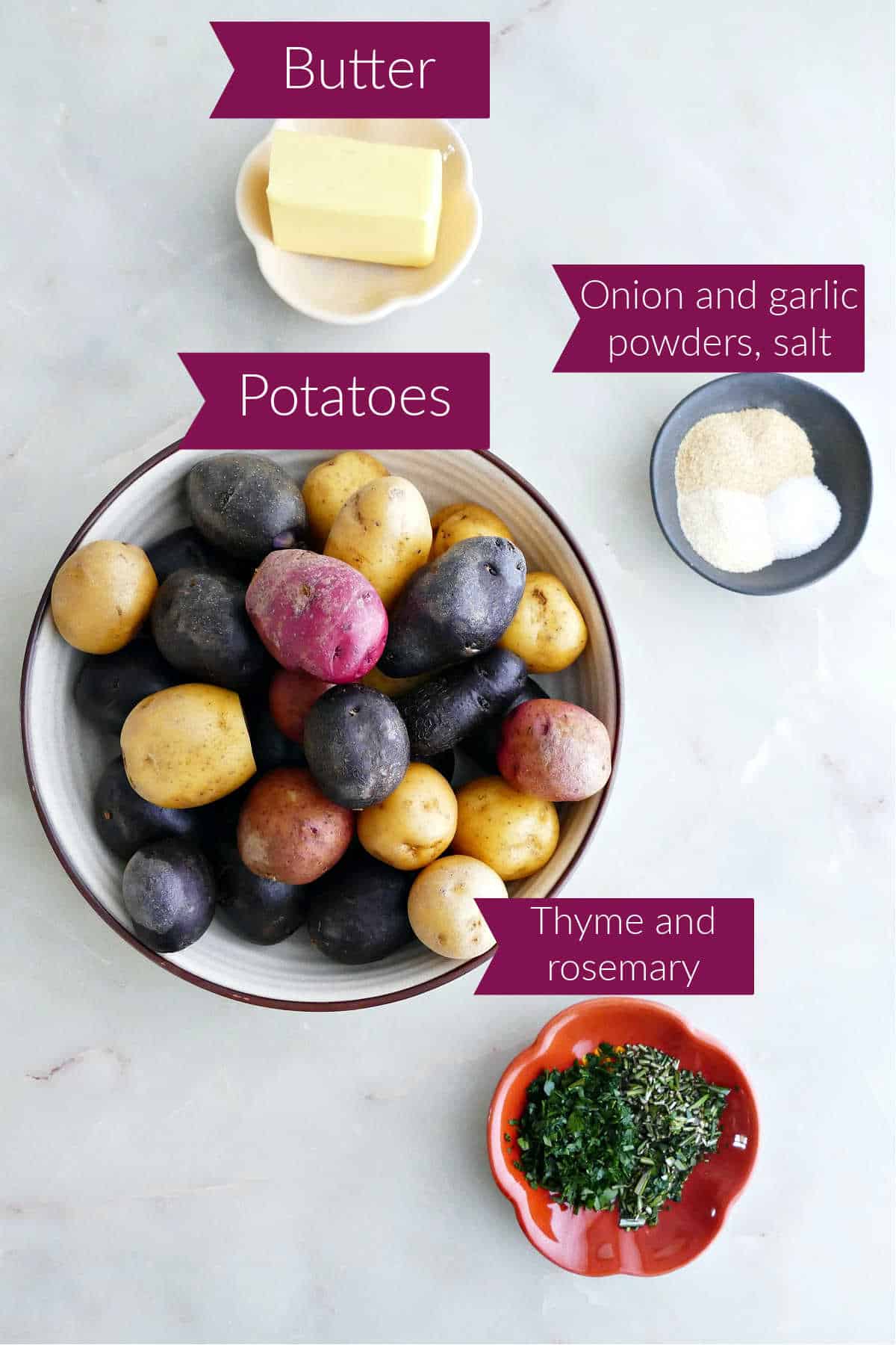 Butter, spices, rainbow baby potatoes, and fresh herbs in bowls with labels.