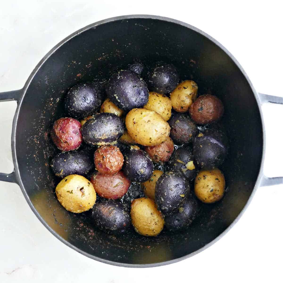 Roasted potatoes in a dutch oven after coming out of the oven.