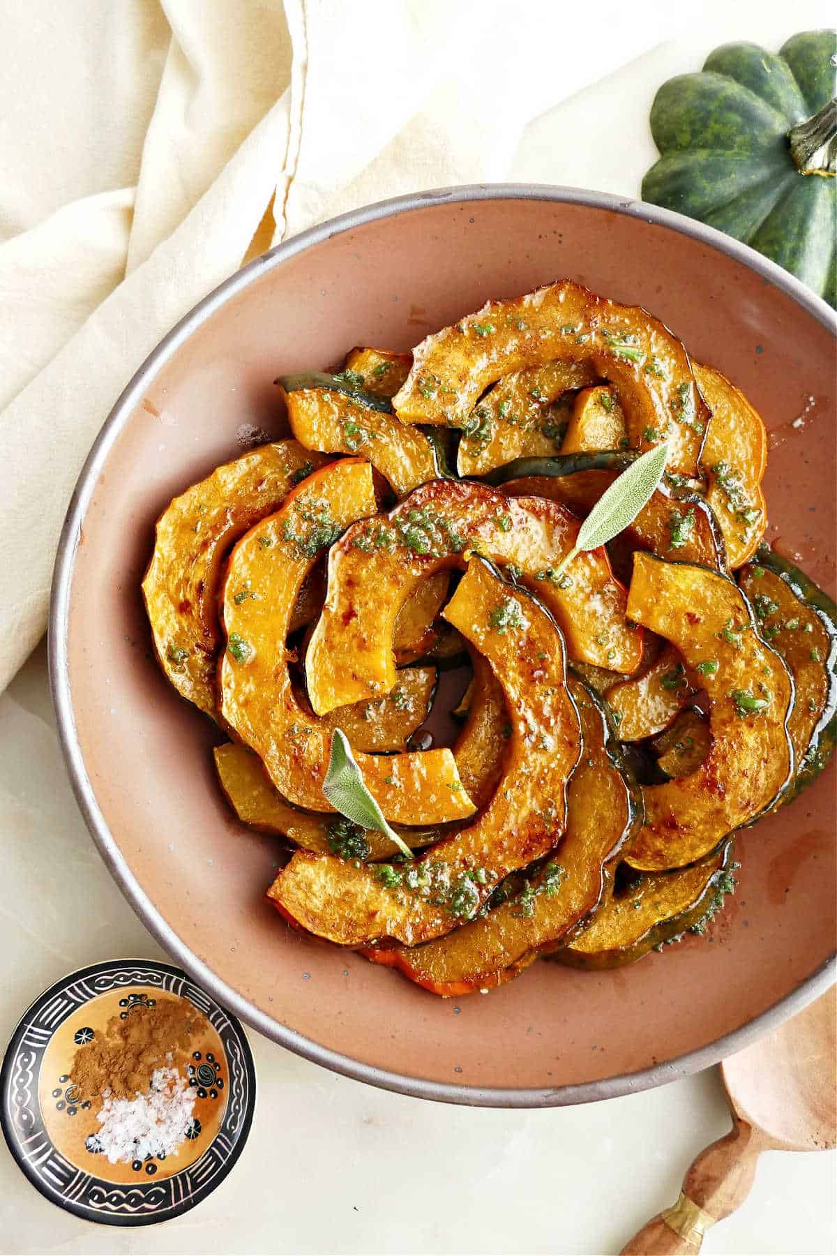 Baked acorn squash with sage butter in a serving dish.