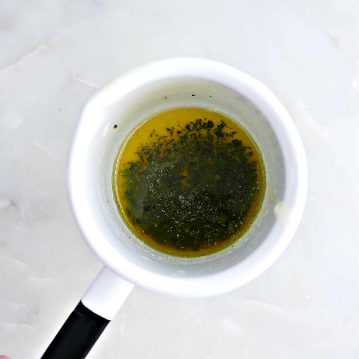 Butter melted in a dish mixed with chopped sage.