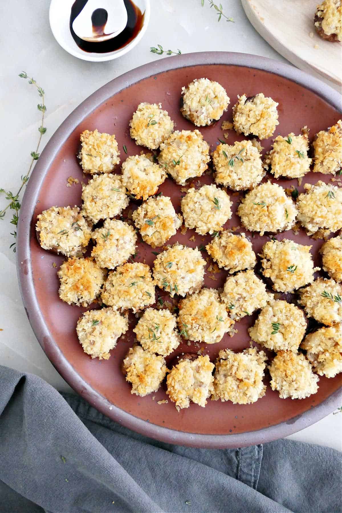 Mushrooms stuffed with boursin cheese and breadcrumbs on a serving plate.
