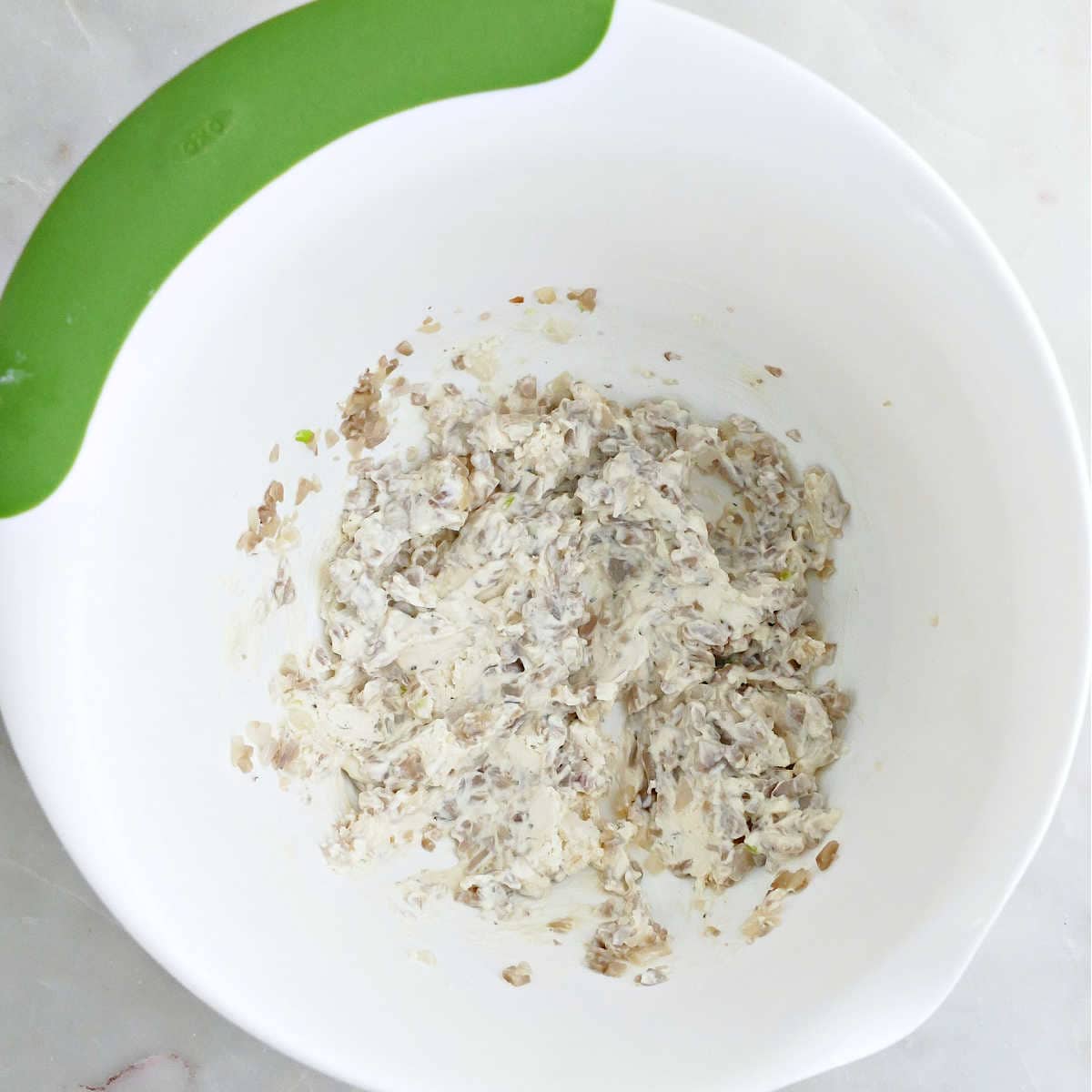 Cheese, garlic, shallots, and mushrooms stems mixed together in a bowl.