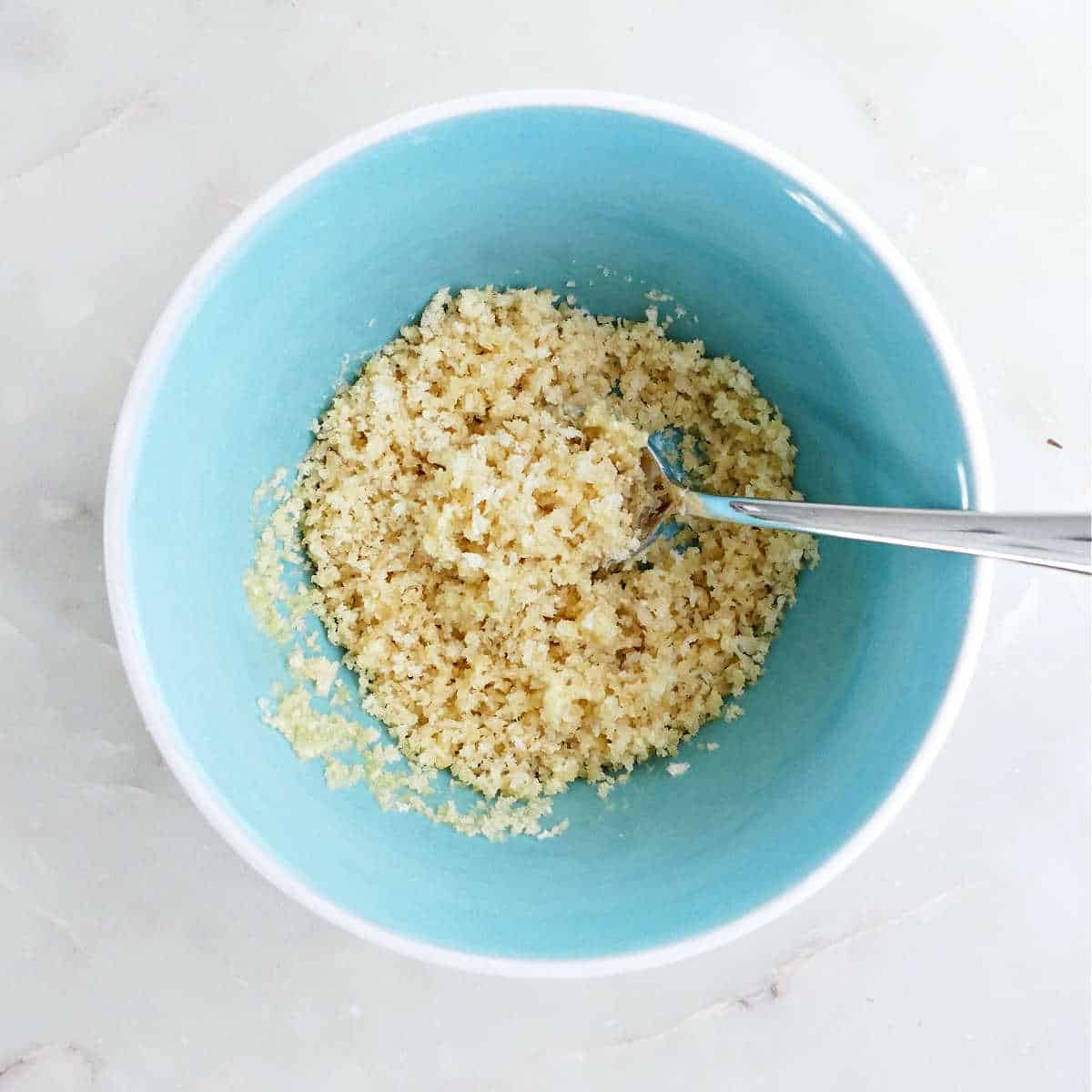 Panko breadcrumbs mixed with melted butter in a bowl.