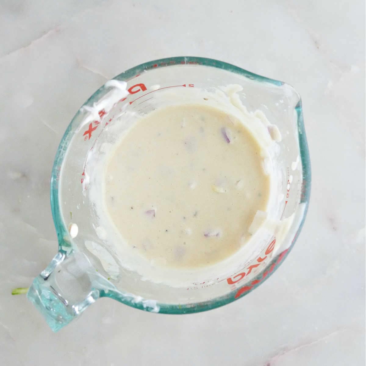 Honey mustard dressing in a glass measuring cup.