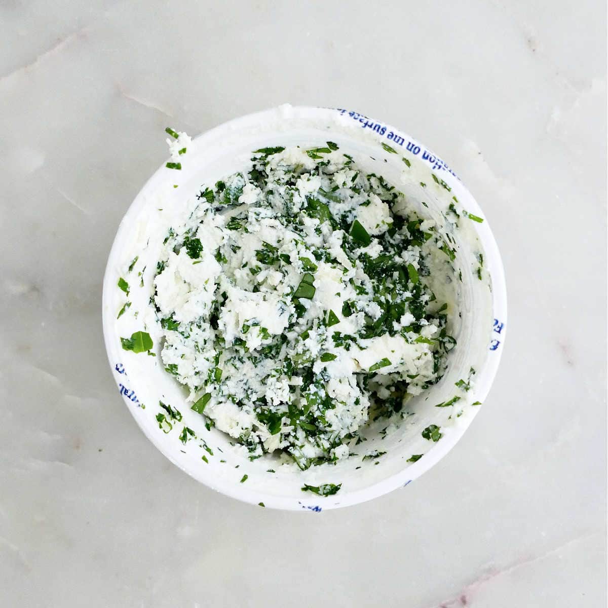 Ricotta mixed with chopped parsley and basil in a bowl.