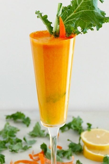 Carrot juice cocktail in a champagne flute.