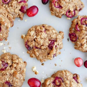 Oatmeal walnut cookies with fresh cranberries on a counter.