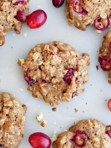 Oatmeal walnut cookies with fresh cranberries on a counter.