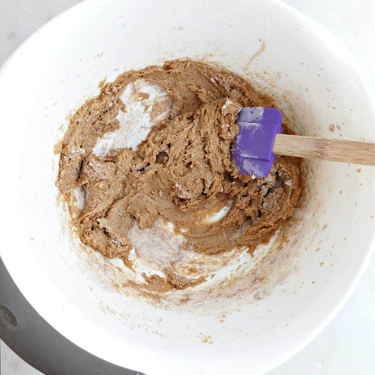 Dry ingredients for cookies being folded into wet batter with a rubber spatula.