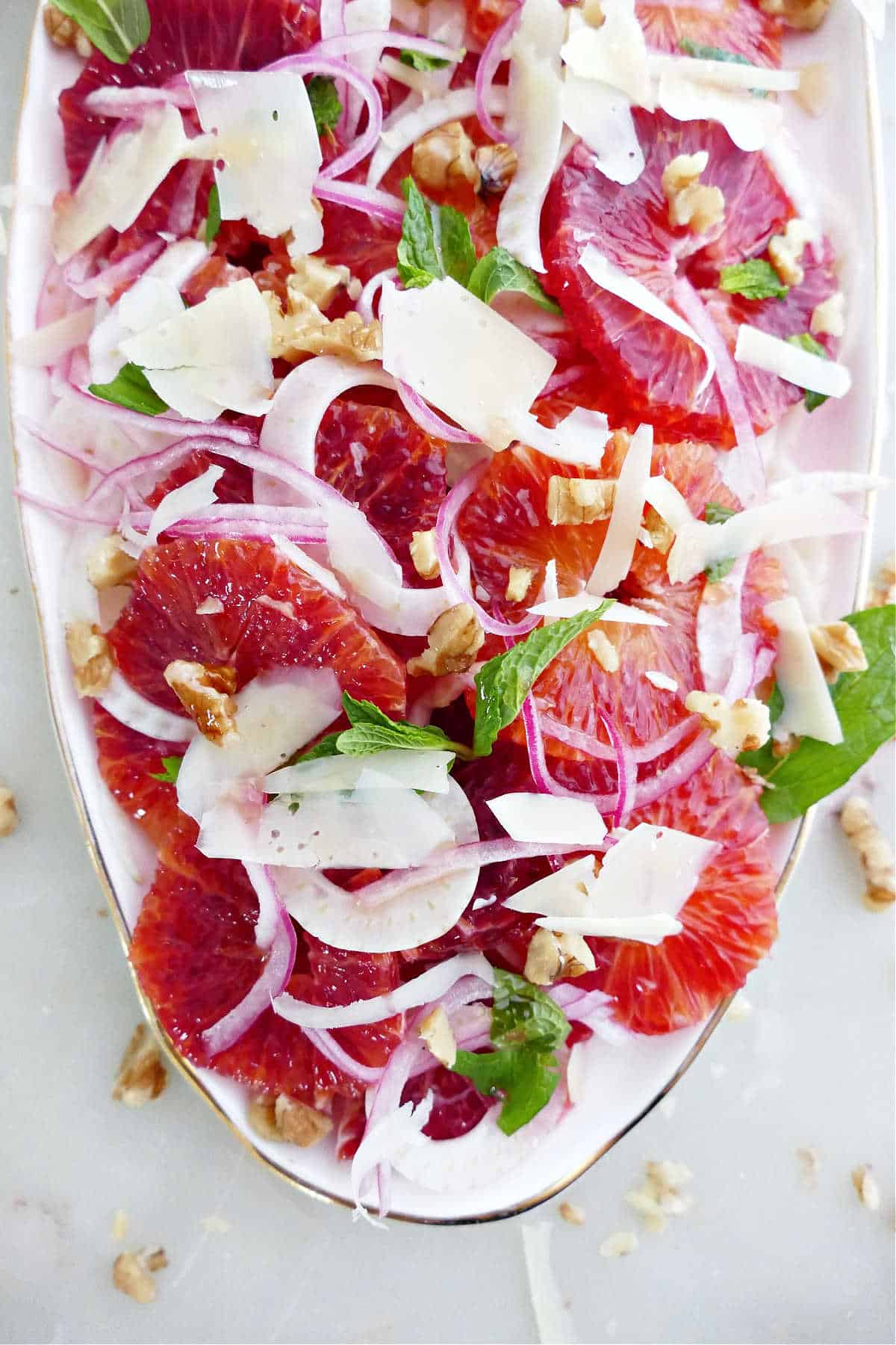 Blood oranges with fennel, onion, mint, walnuts, and parmesan on a serving tray.