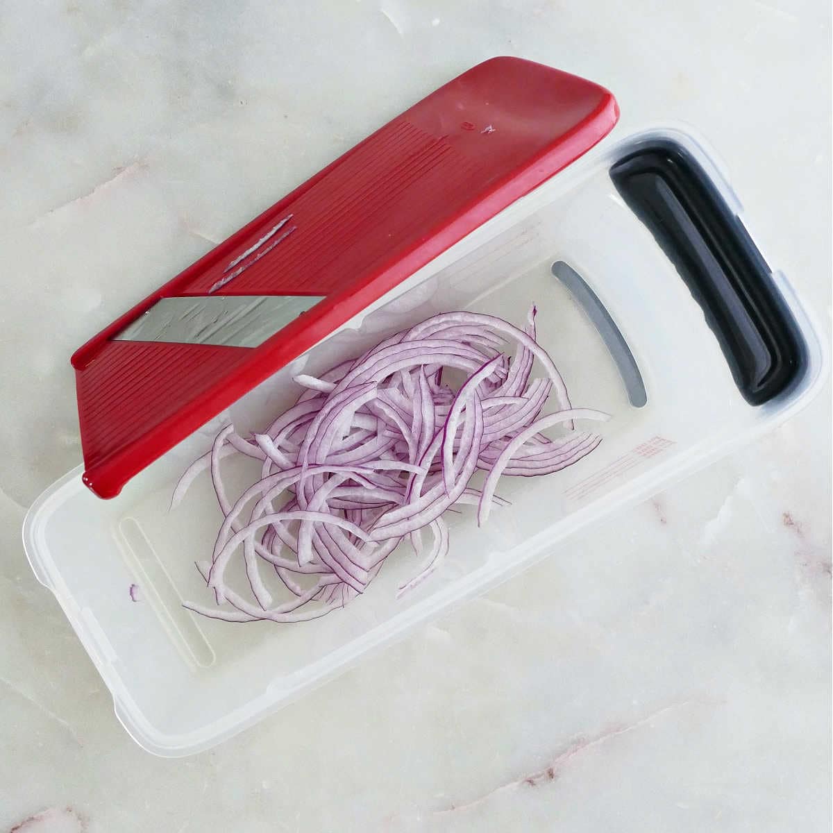 Thin pieces of red onion sliced using a mandoline.