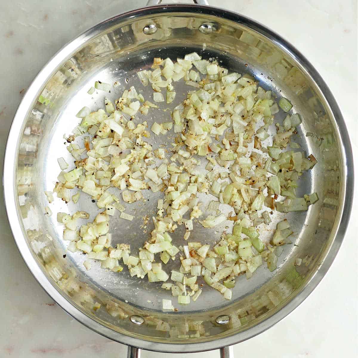 Onion, garlic, salt, and pepper cooking in olive oil in a skillet.