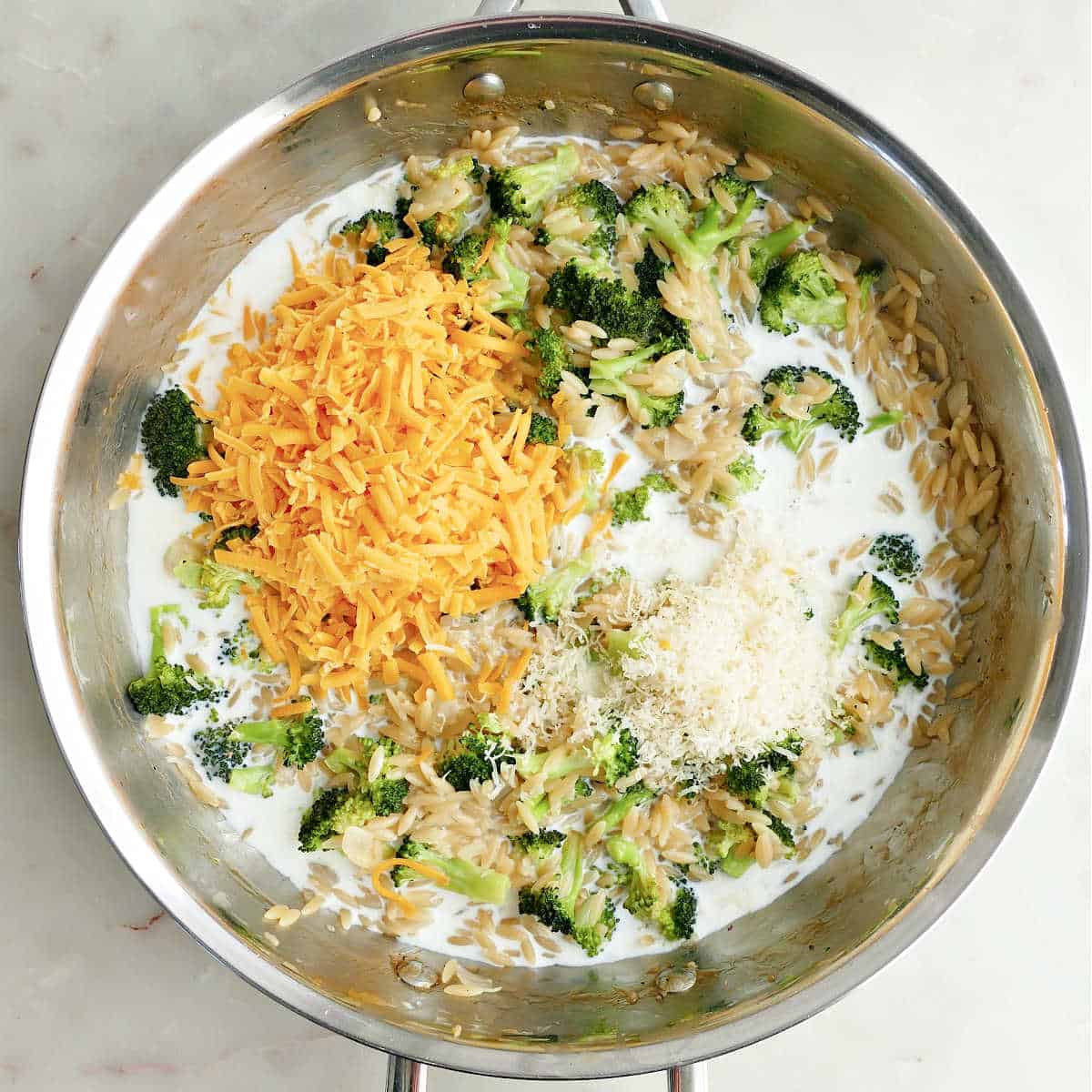 Cheddar cheese, parmesan cheese, and milk added to broccoli orzo.