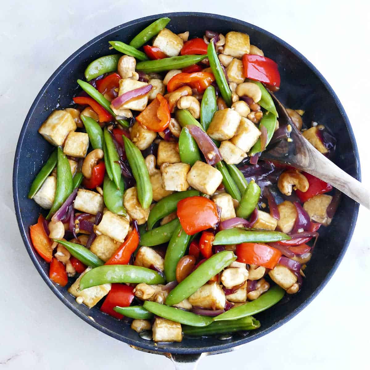 Cashew stir fry with tofu and sauce added to skillet.