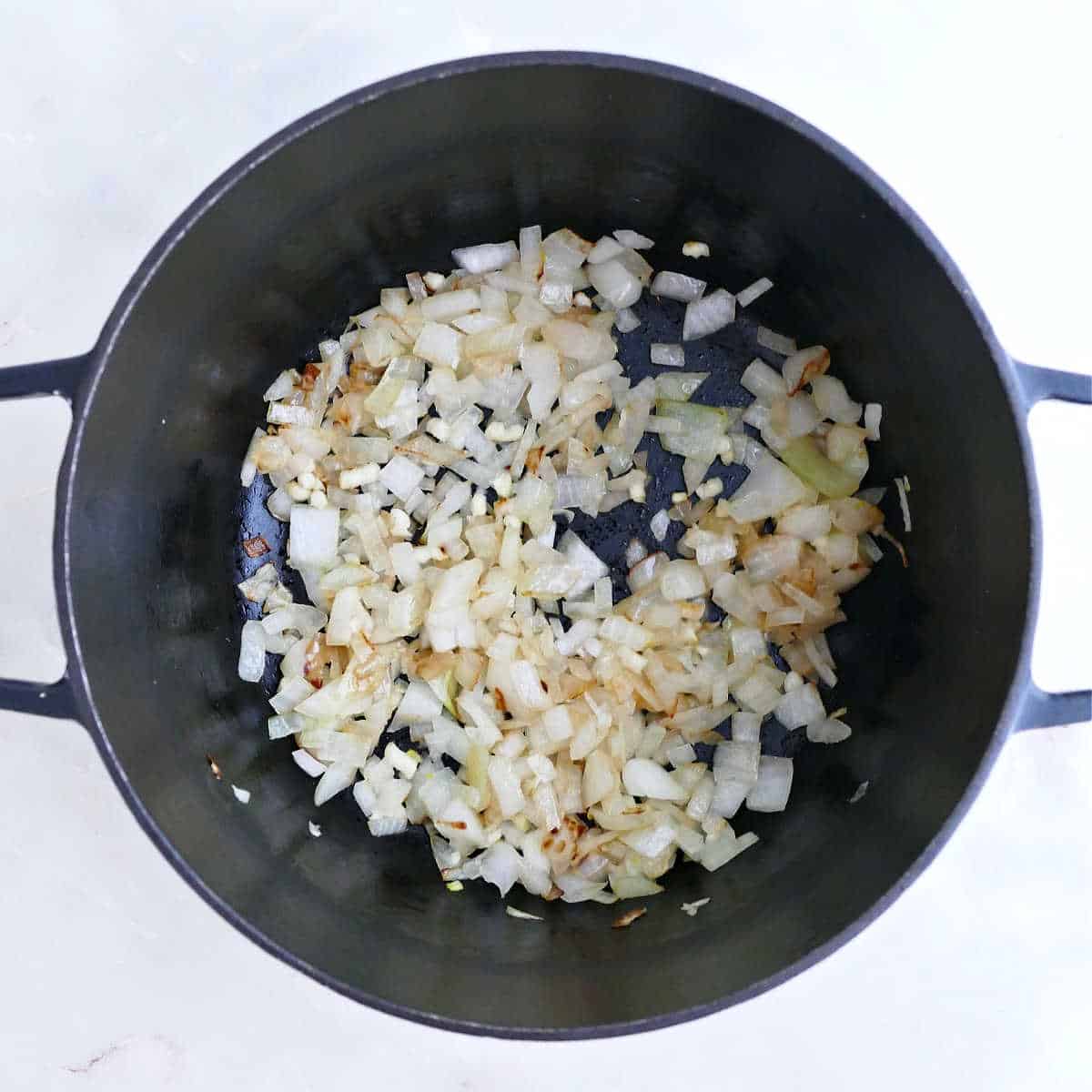 Onions and garlic cooking in oil in a soup pot.