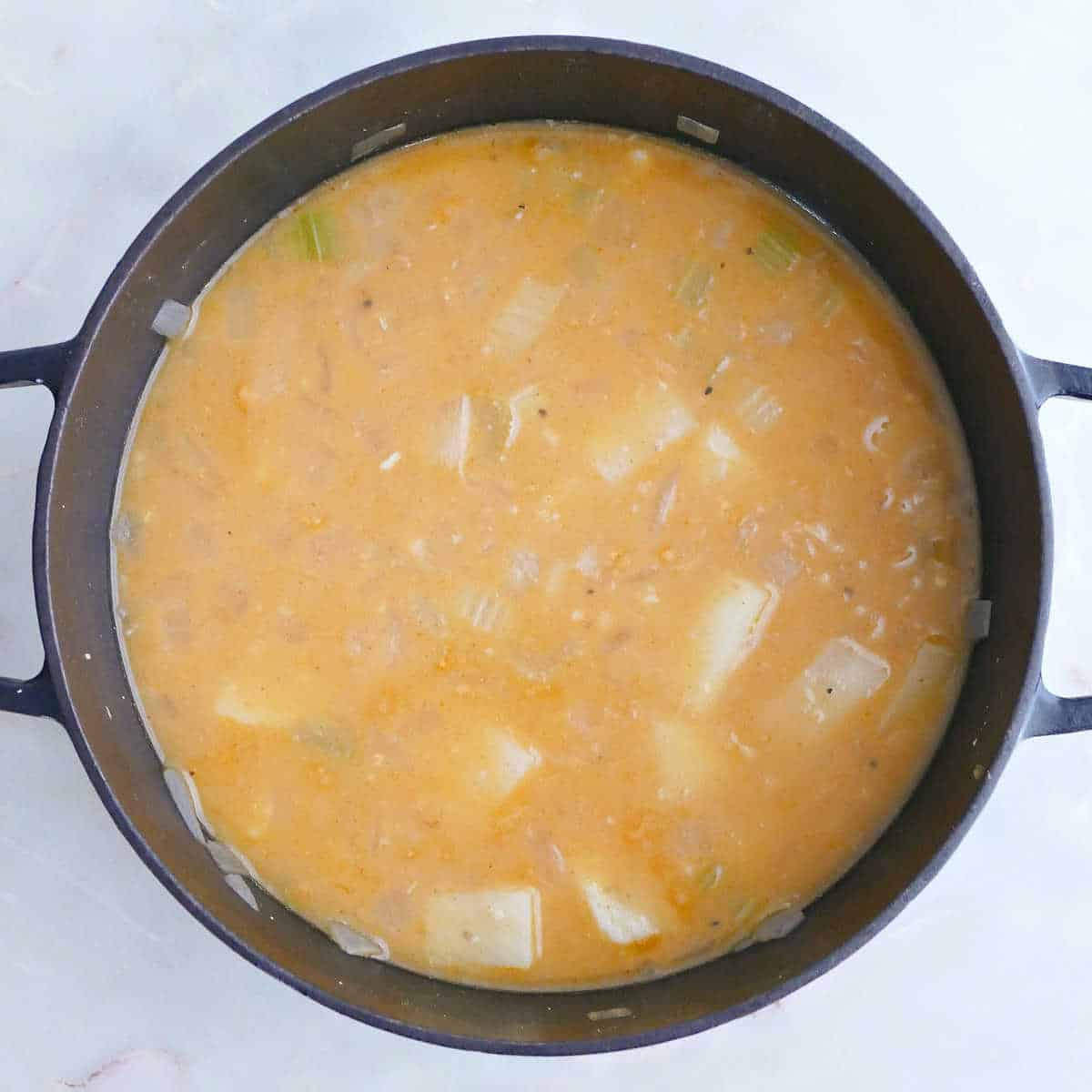 Potato white bean soup after cooking in a pot before being blended.