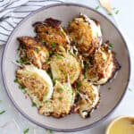 Roasted savoy cabbage wedges in a bowl surrounded by ingredients and napkin.