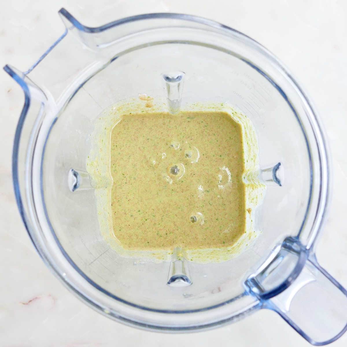 Batter for spinach banana pancakes in a blender on a counter.