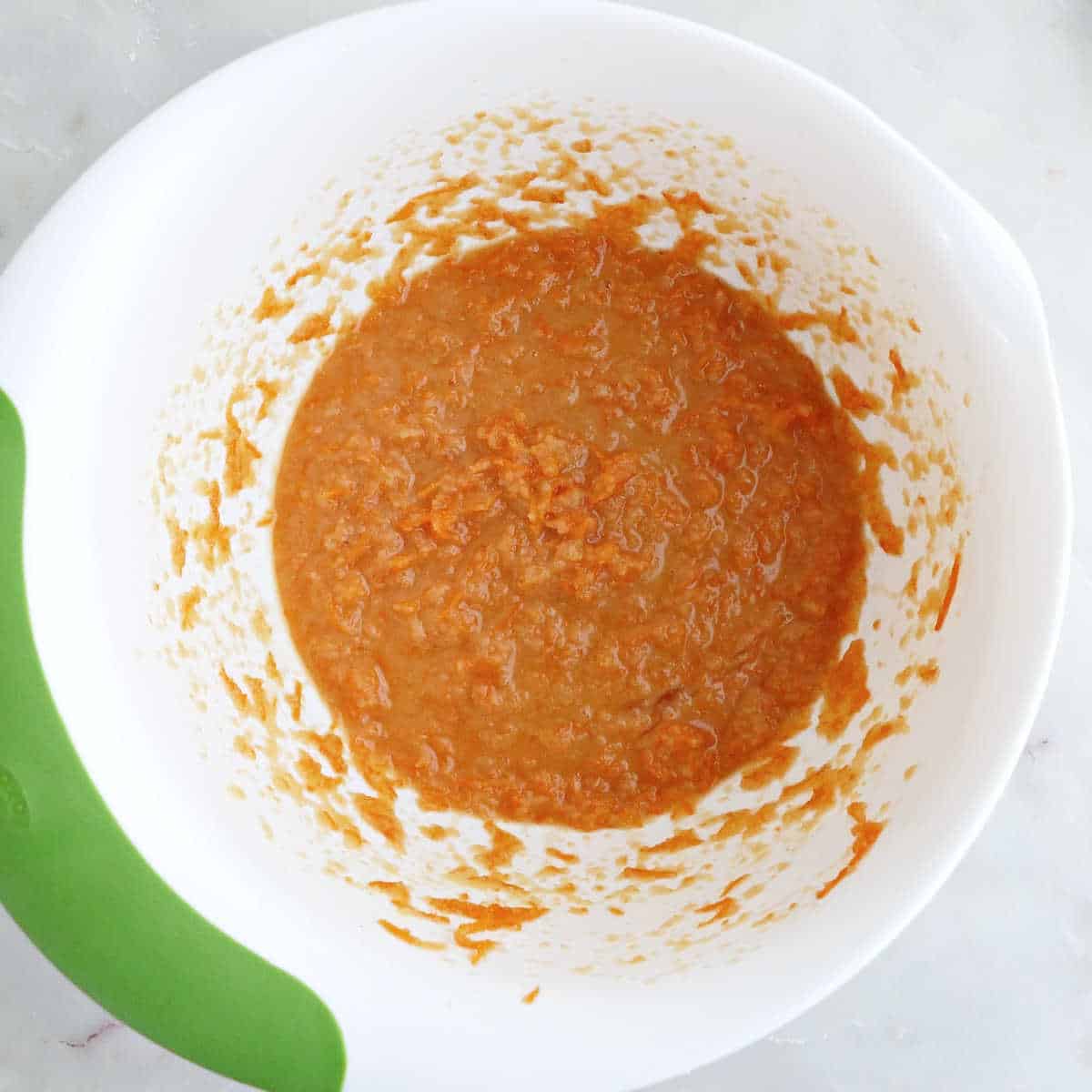 Wet ingredients for carrot applesauce muffins whisked together in a bowl.