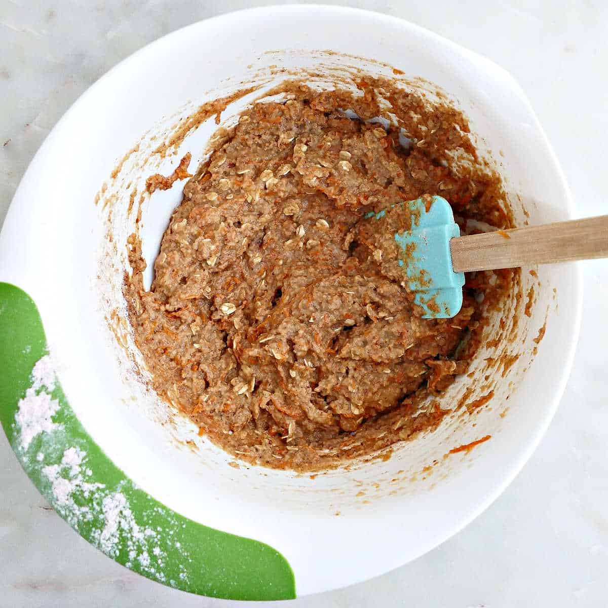Oats and flour being mixed into batter for healthy muffins.