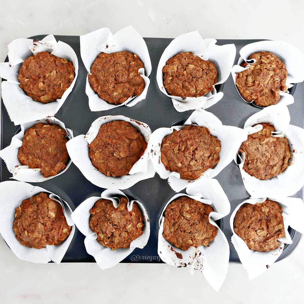 Lower sugar muffins in parchment in a tray after baking in the oven.
