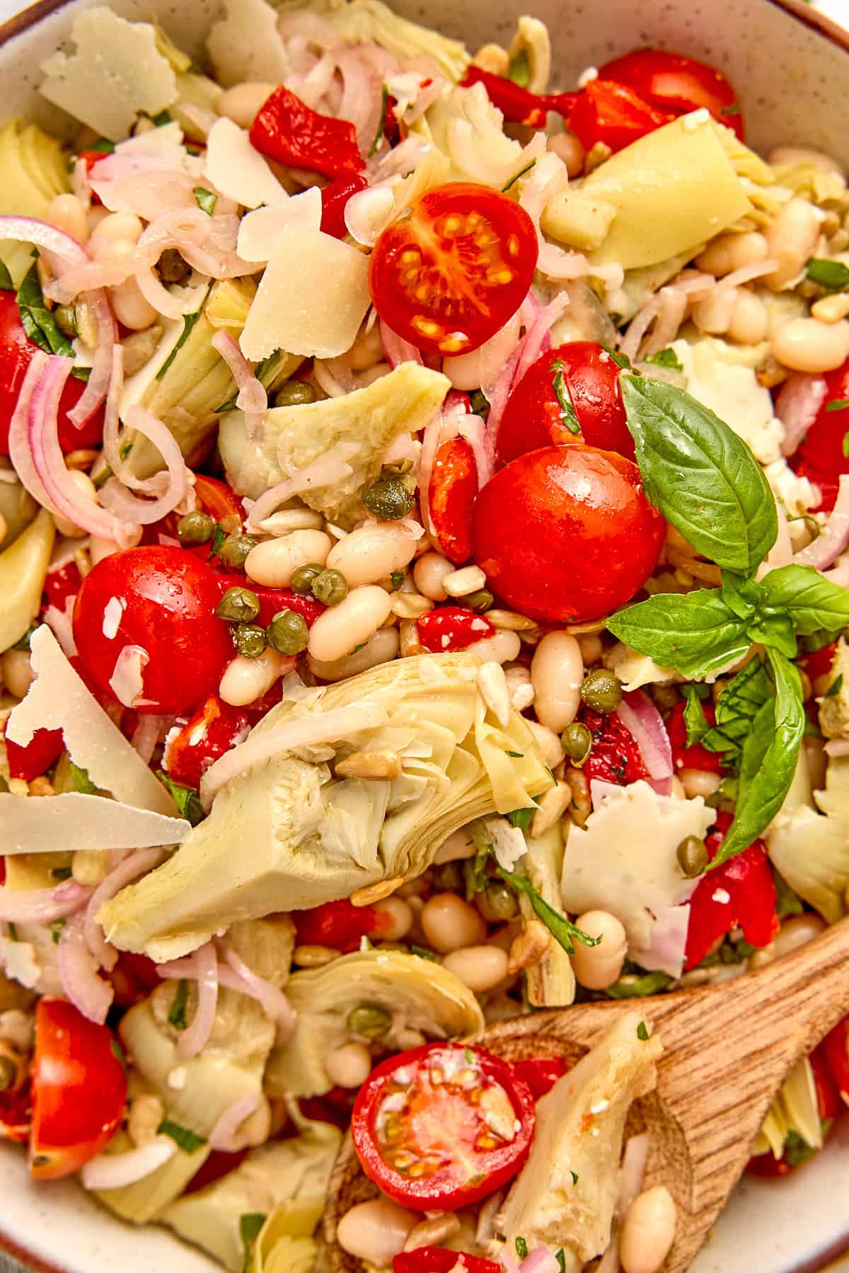 Cold salad using canned artichoke hearts in a bowl topped with fresh basil.