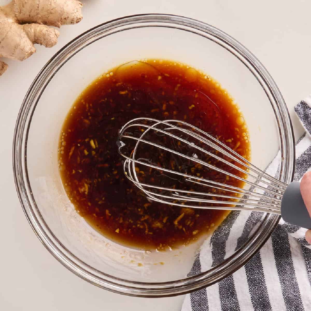 Stir fry sauce being whisked in a glass bowl.
