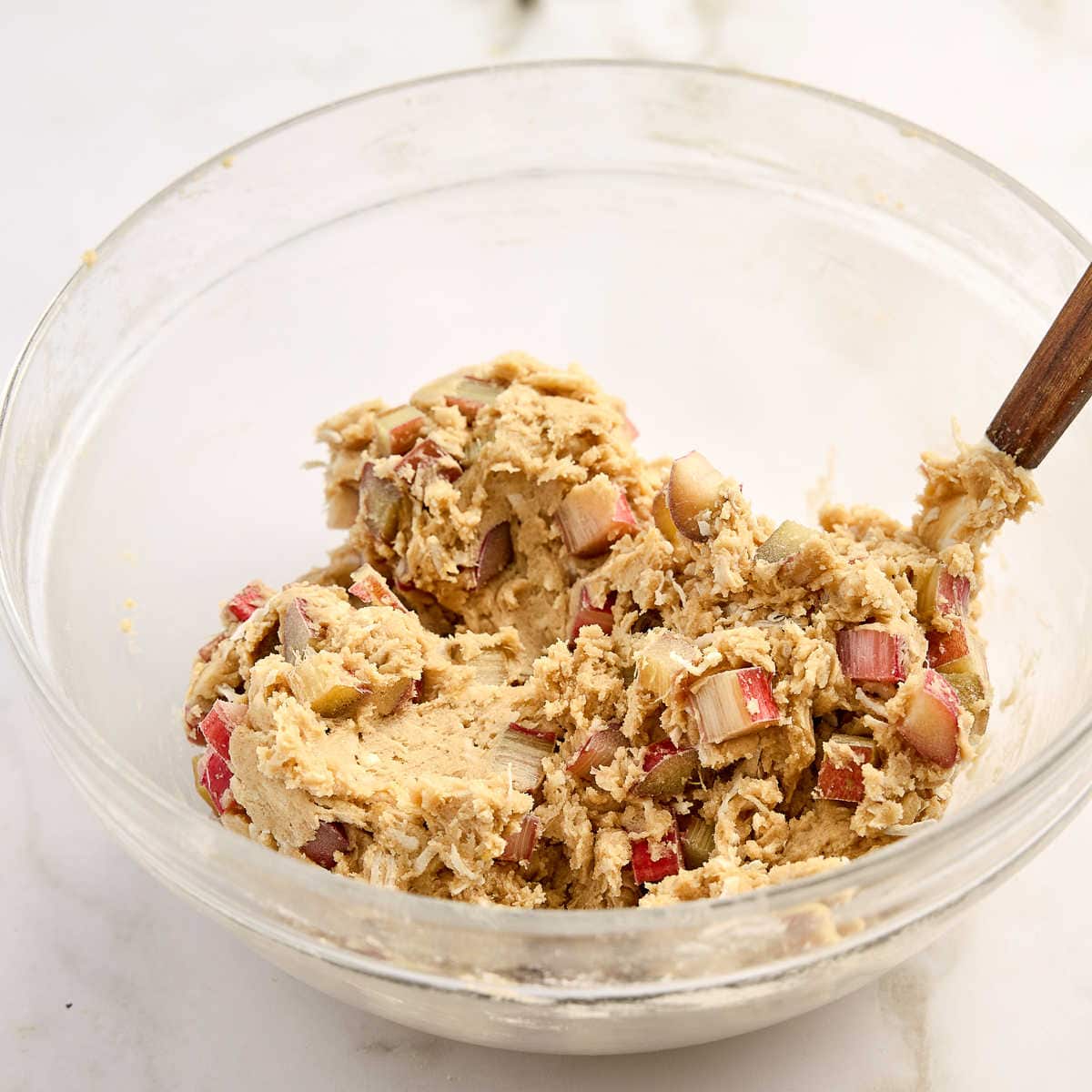 Rhubarb cookie batter mixed in a bowl with a rubber spatula.