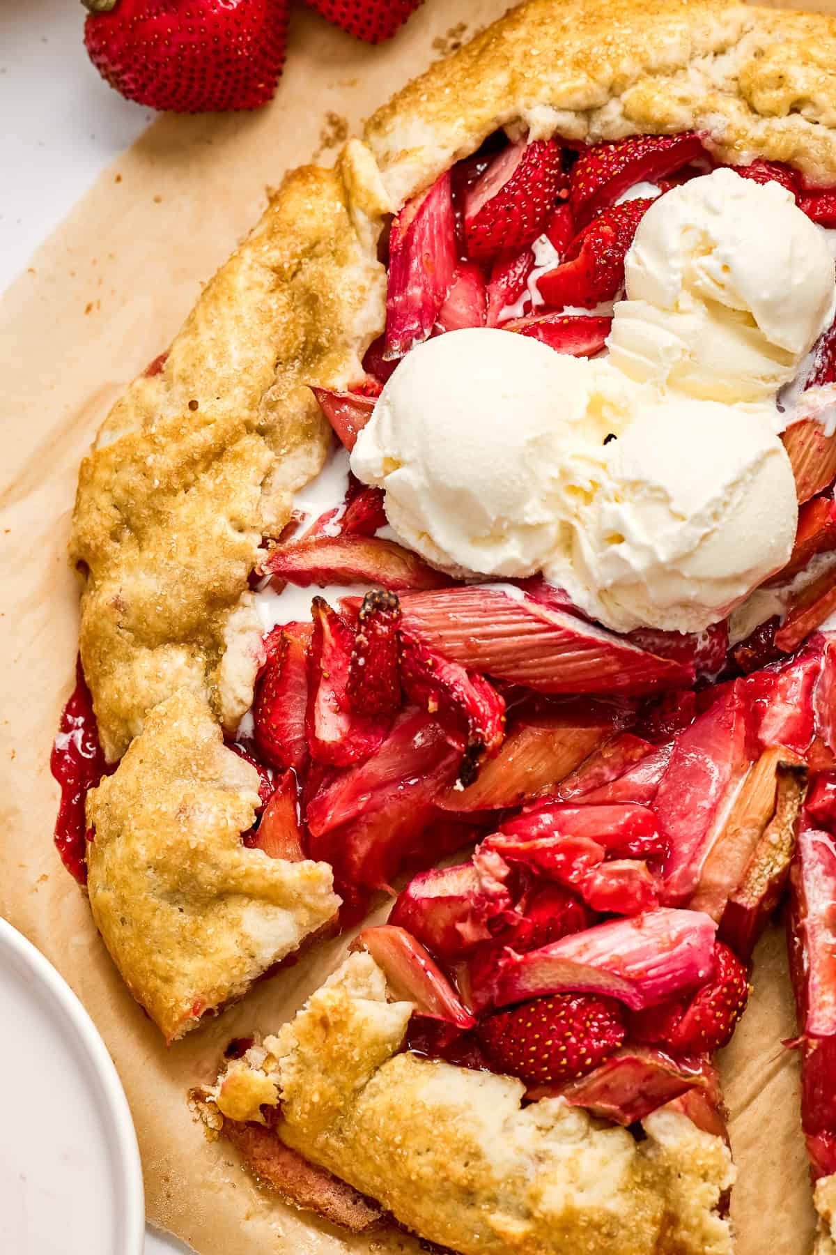 Slices of strawberry rhubarb tart topped with vanilla ice cream.