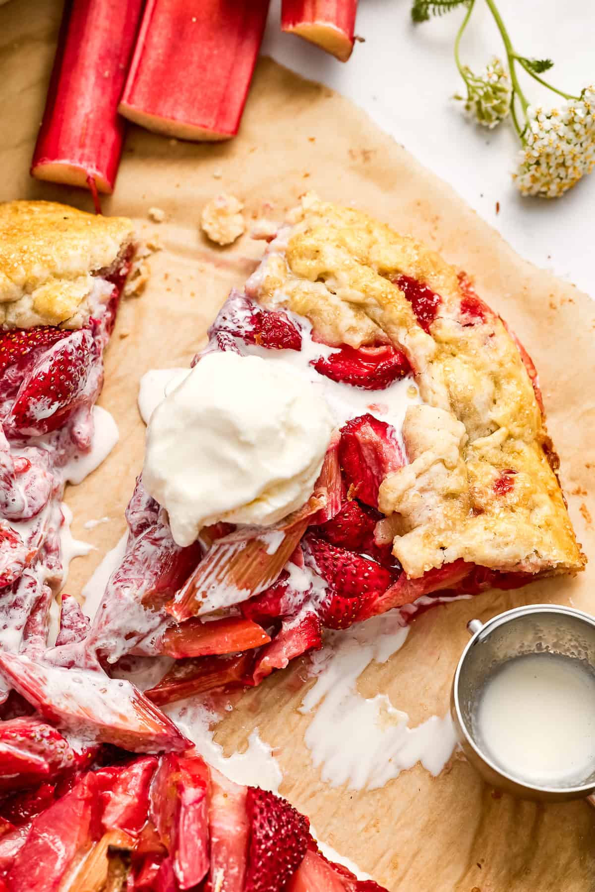 Slice of strawberry rhubarb tart with vanilla ice cream next to ice cream scoop.