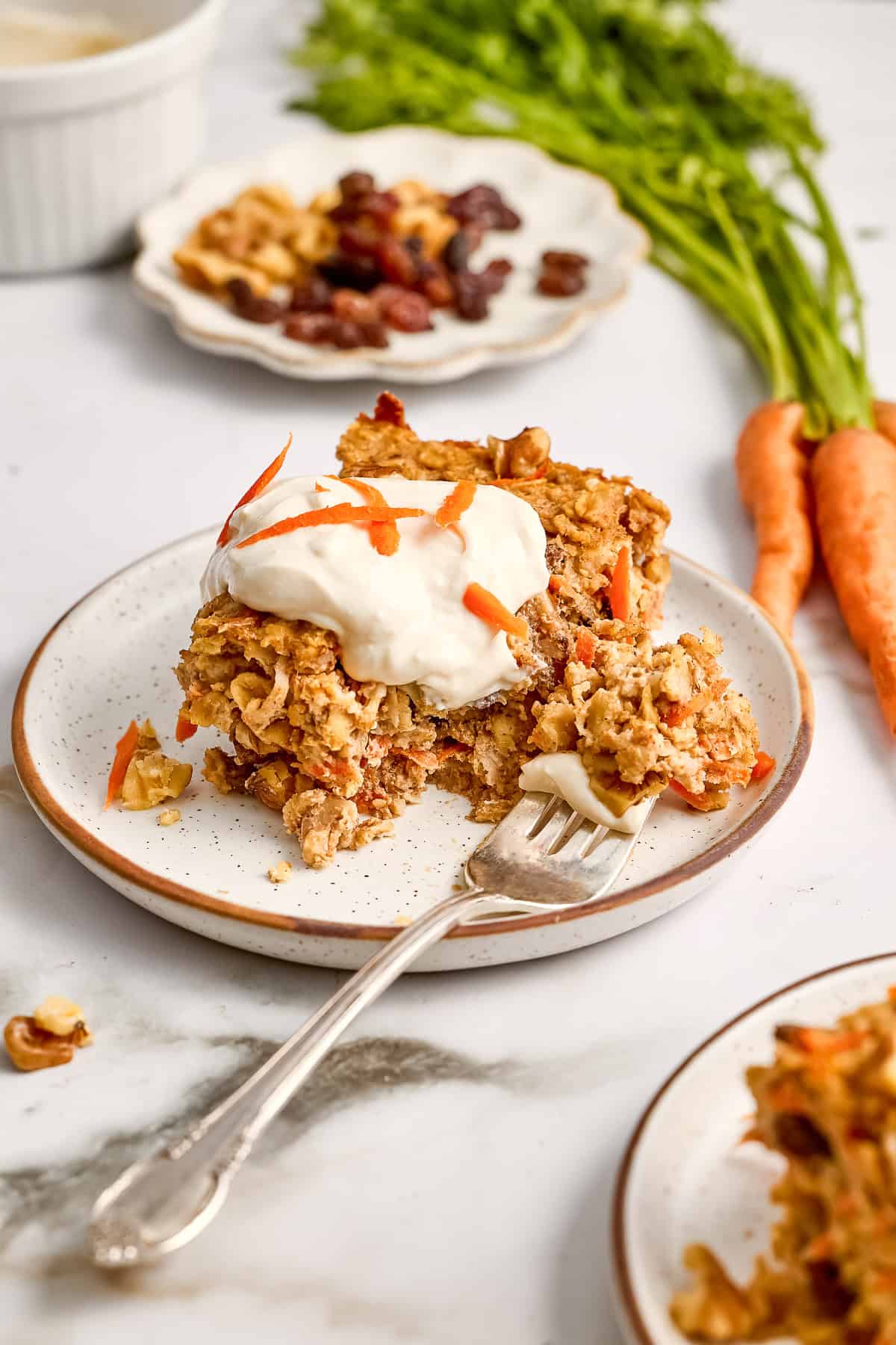 Carrot cake oats with frosting on a plate with a fork with a bite on it.